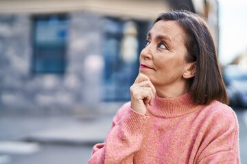 Middle age woman standing with doubt expression at street