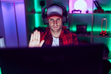 Young caucasian man playing video games with open hand doing stop sign with serious and confident...