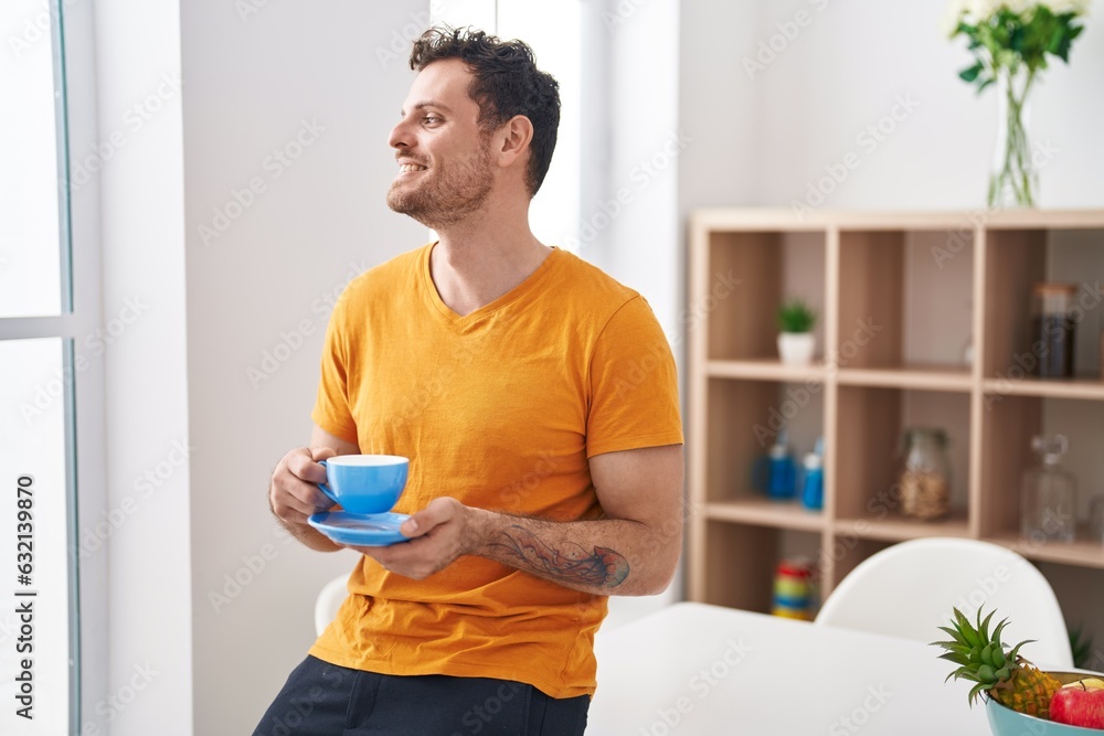 Canvas Prints young hispanic man drinking coffee sitting on table at home