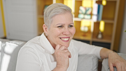 Middle age grey-haired woman smiling confident sitting on sofa at home
