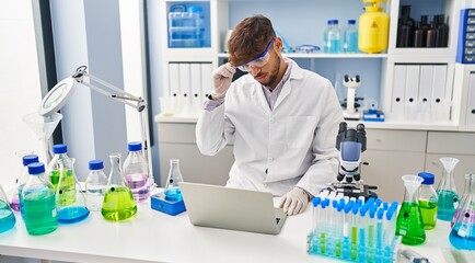 Young arab man scientist stressed using laptop working at laboratory