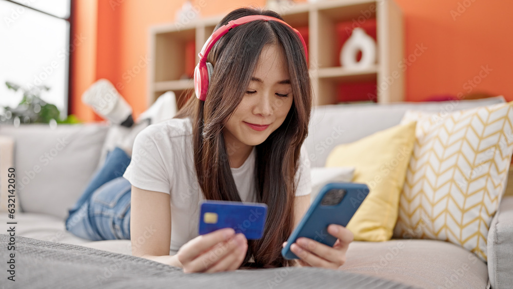 Sticker young chinese woman shopping with smartphone and credit card listening to music at home