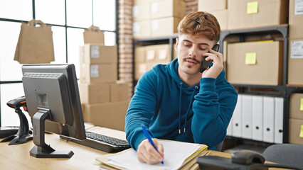 Young hispanic man ecommerce business worker talking on smartphone writing on package at office