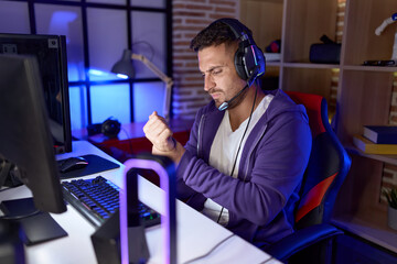 Young hispanic man streamer stressed suffering for wrist pain at gaming room