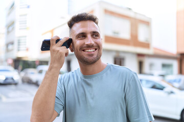 Young hispanic man smiling confident listening audio message by the smartphone at street