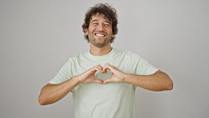 Young hispanic man smiling confident doing heart gesture with hands over isolated white background