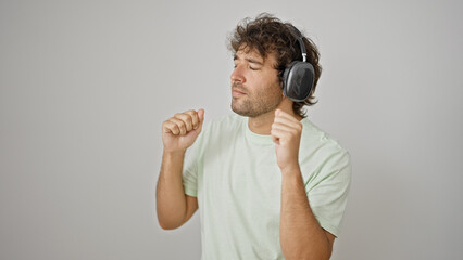 Young hispanic man listening to music and dancing over isolated white background