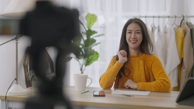 Selling Online Shopping e-Commerce asian youtuber influencer concept.Portrait confident lovely Asian women talking on camera in workplace to make video blog for sales clothes online. 