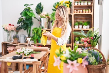 Young blonde woman florist smiling confident wearing gloves at florist