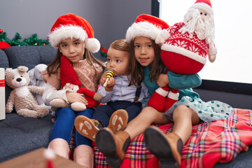 Group of kids hugging each other sitting on sofa by christmas decoration at home