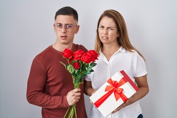 Mother and son holding mothers day gift clueless and confused expression. doubt concept.