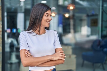 Young beautiful hispanic woman standing with arms crossed gesture at street