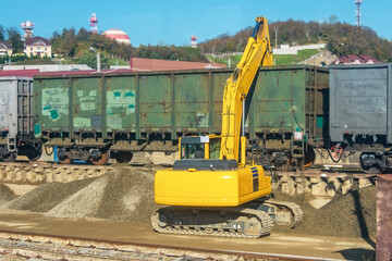 Unloading unloading rubble with an excavator railway carriage wagons with bulk cargo gravel, sand at the station.