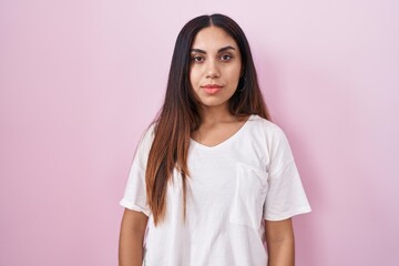 Fototapeta premium Young arab woman standing over pink background relaxed with serious expression on face. simple and natural looking at the camera.