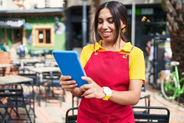 Young beautiful arab woman waitress smiling confident using touchpad at coffee shop terrace