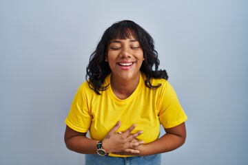 Hispanic woman standing over blue background smiling and laughing hard out loud because funny crazy...