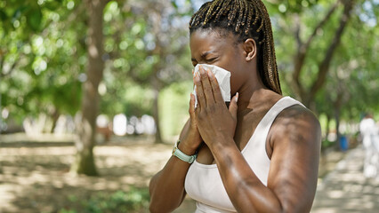 African american woman using tissue with pollen allergy at park