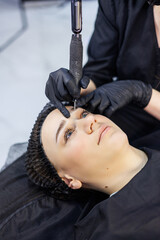 Permanent make-up of eyebrows. Woman professional permanent make-up artist with a permanent make-up...
