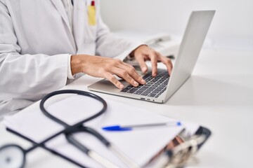 Young hispanic man doctor using laptop at clinic