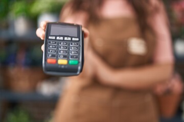 Young beautiful hispanic woman florist holding data phone at flower shop