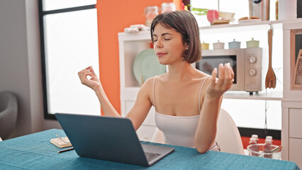 Young beautiful hispanic woman doing yoga exercise relaxing on table at dinning room