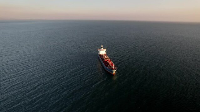 Aerial drone approaching a large marine vessel used for logistics import export, shipping or transportation