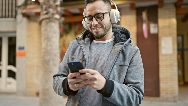 Hispanic man smiling confident listening to music using smartphone at street