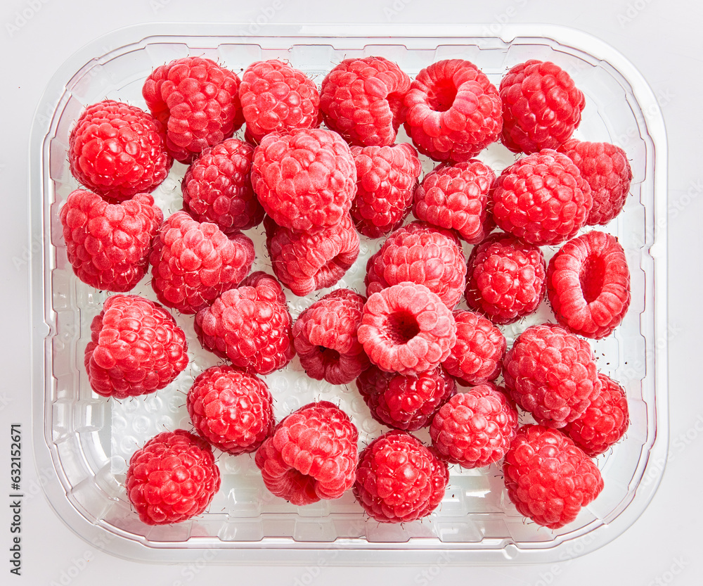 Poster  Delicious group of raspberries on plastic box over isolated white background