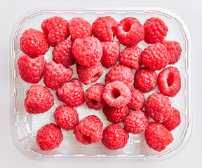  Delicious group of raspberries on plastic box over isolated white background