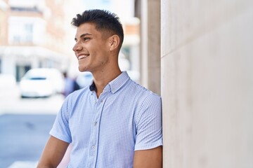 Young hispanic man smiling confident looking to the side at street