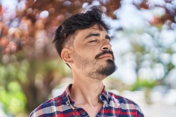 Young hispanic man breathing at park