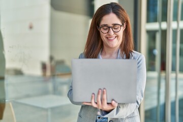 Young woman business worker smiling confident using laptop at street