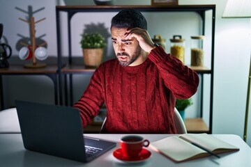 Young hispanic man with beard using computer laptop at night at home worried and stressed about a...