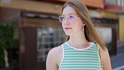 Young blonde woman looking to the side with serious expression at coffee shop terrace