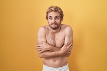 Fototapeta premium Caucasian man standing shirtless wearing sun screen shaking and freezing for winter cold with sad and shock expression on face