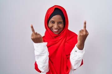 Young arab woman wearing traditional islamic hijab scarf showing middle finger doing fuck you bad expression, provocation and rude attitude. screaming excited