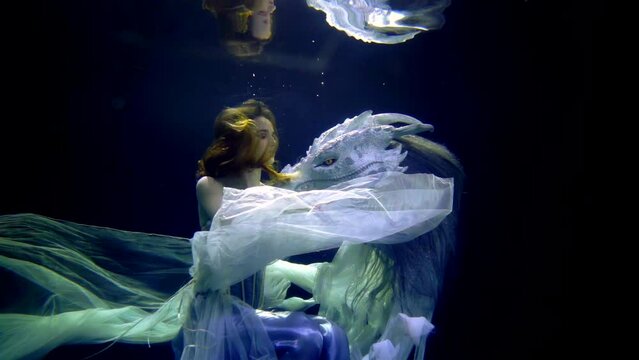 underwater medium shot with beautiful young woman and scary fabulous dragon, mysterious depth