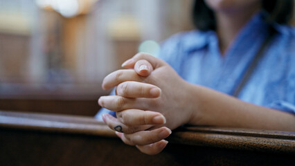 Young beautiful hispanic woman praying on a church bench at St. Karl BorromÃ¤us church