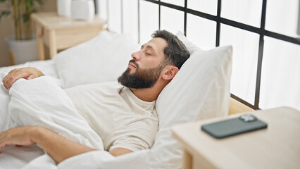 Fototapeta premium Young hispanic man lying on bed sleeping at bedroom