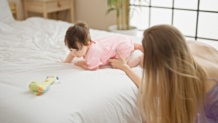 Mother and daughter playing on bed with dino toy at bedroom