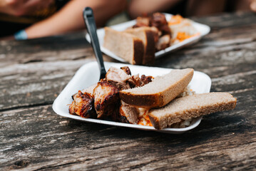 Simple portion of street food, meat salad and bread in a cup on a wooden table