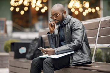 Black man sitting on a bench and using a phone
