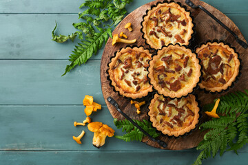 Obraz na płótnie Canvas Savory hands pie with chanterelle mushrooms, cream and cheese on cutting board on rustic old wooden table background. Homemade tarts with seasonal chanterelle mushrooms. Rustic style. Top view.