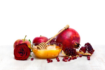 Honey in glass bowl, red apples, garnets, red rose on white wooden table on a white background with...