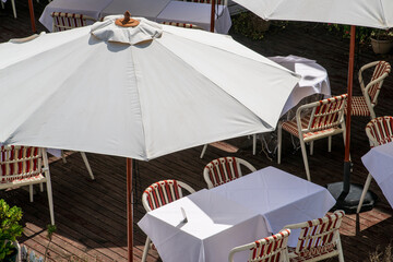 Cafe umbrellas, tables and chairs in sunlight