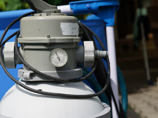 Close-up photo of filtration with swimming pool. We can see the top part of the device where the...