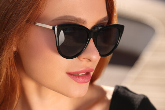 Beautiful woman in sunglasses outdoors on sunny day, closeup