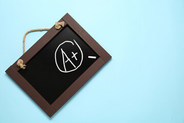 School grade. Small blackboard with chalked letter A and plus symbol on light blue background