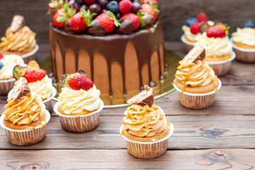 Gorgeous cupcakes with peanut butter, salted caramel and chocolate bar on rustic wooden background