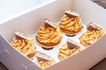 Gorgeous cupcakes with peanut butter, salted caramel and chocolate bar on cardboard gift box